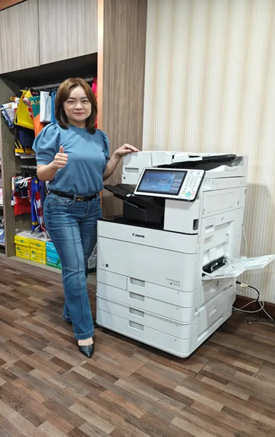 A happy customer next to her Canon copier at a flag manufacturer