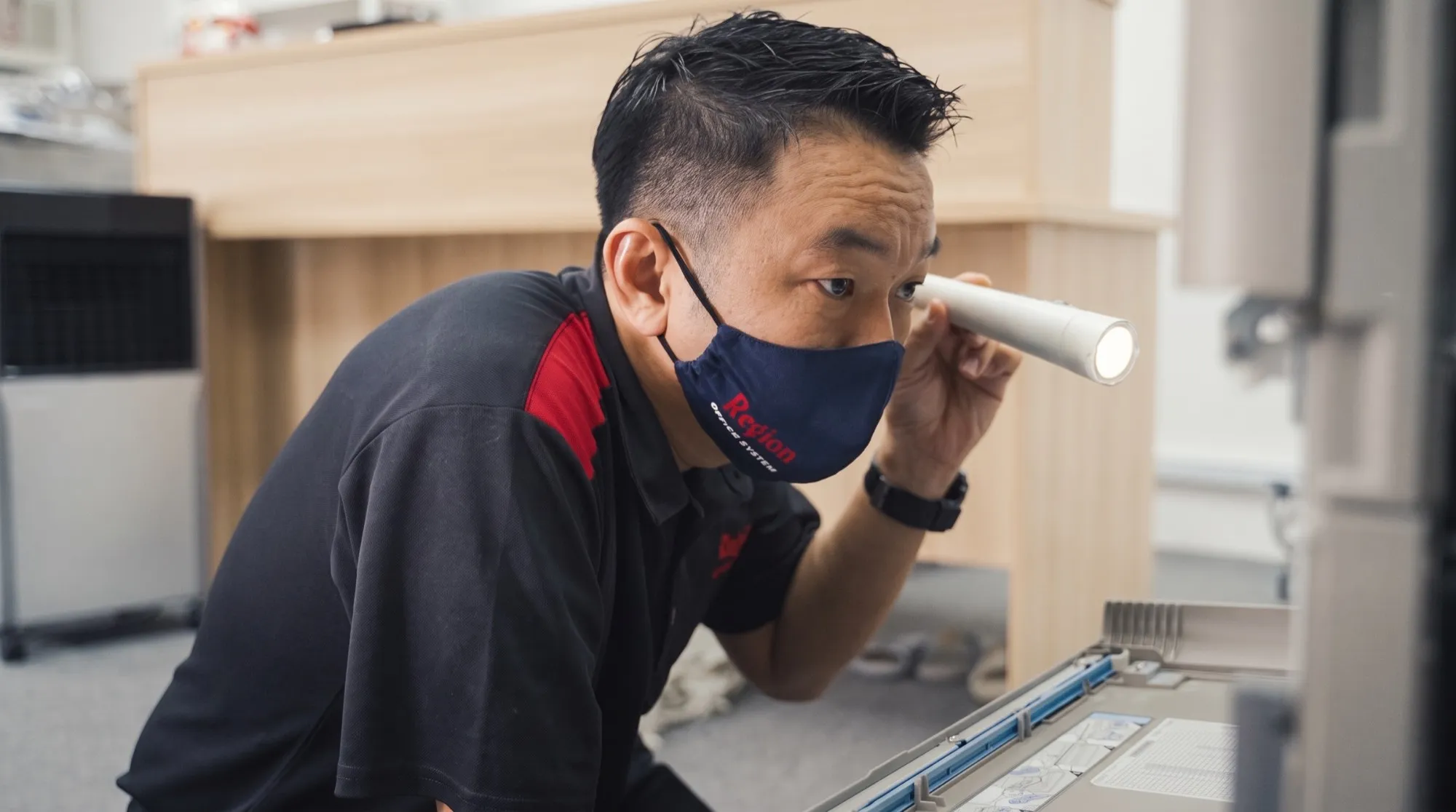 James Wong inspecting a copier with a torch